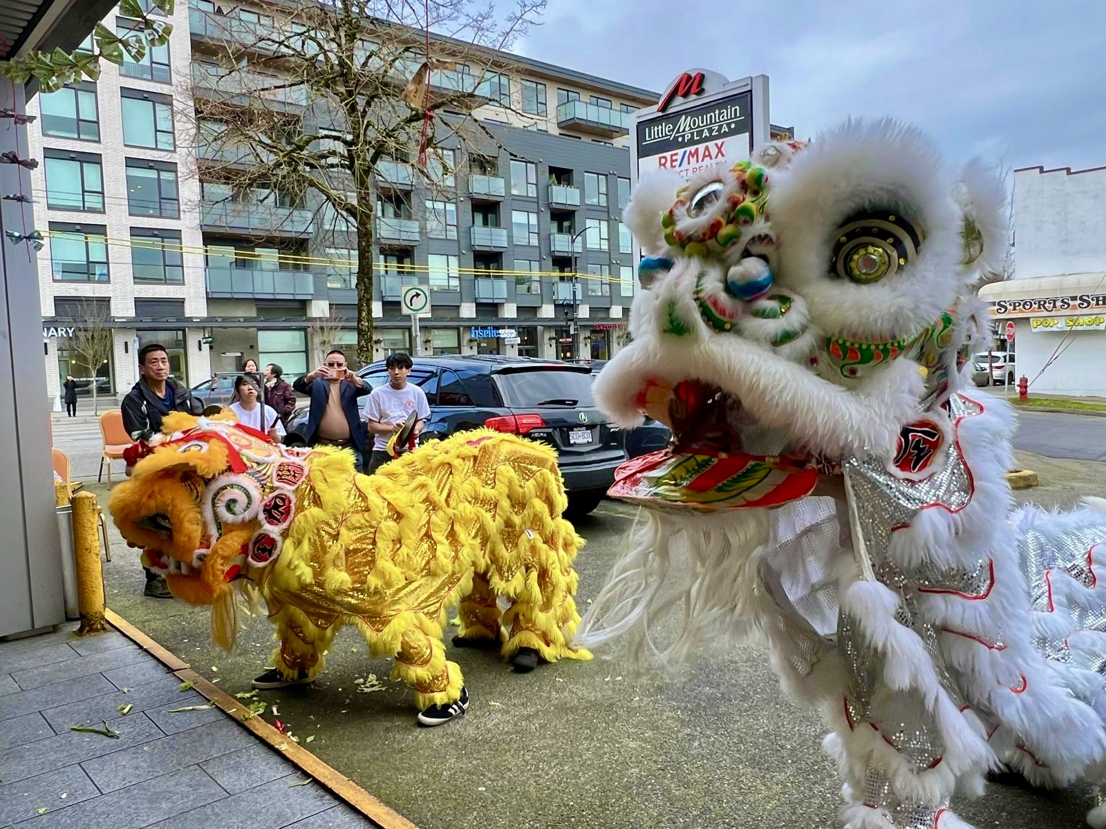 Lion dance team performing outside a storefront during a grand opening, firecrackers on the ground